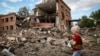 Lubov Jarova holds her dog, Victory, as she walks among the rubble of a school on September 7 in the frontline town of Orikhiv in Ukraine&#39;s Zaporizhzhya region. Jarova credits her dog with saving her life.