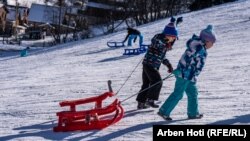 Fëmijë duke tërhequr një sajë në qendrën e skijimit, në Bogë.