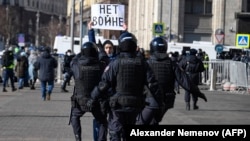 Police officers detain a man holding a placard reading "No to war" during a protest against Russia's full-scale invasion of Ukraine, in central Moscow on March 13, 2022.

