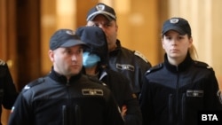 Красимира Трифонова (с качулка и маска), обвинена в убийството на своя зет Пейо Пеев, в сградата на съда.