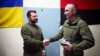 Pe 23 martie, militarii din regiunea Herson i-au oferit președintelui Volodimir Zelenski (stânga) un ceas confecționat dintr-un tun inamic avariat pe a cărui carcasă este reprezentată harta Crimeei