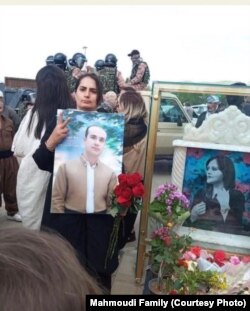 The Wife of Fereydoun Mahmoudi, who was one of the victims of the protests in Iran, holding his picture.