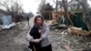 Residents stand among debris on the street outside a house destroyed as a result of a drone attack in Tayirove, Odesa region, on December 17.