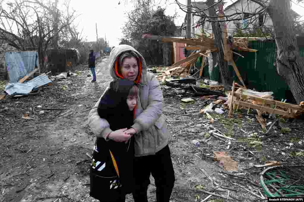 Local residents stand among debris on the street outside a house destroyed as a result of a drone attack in Ukraine&#39;s Odesa region.