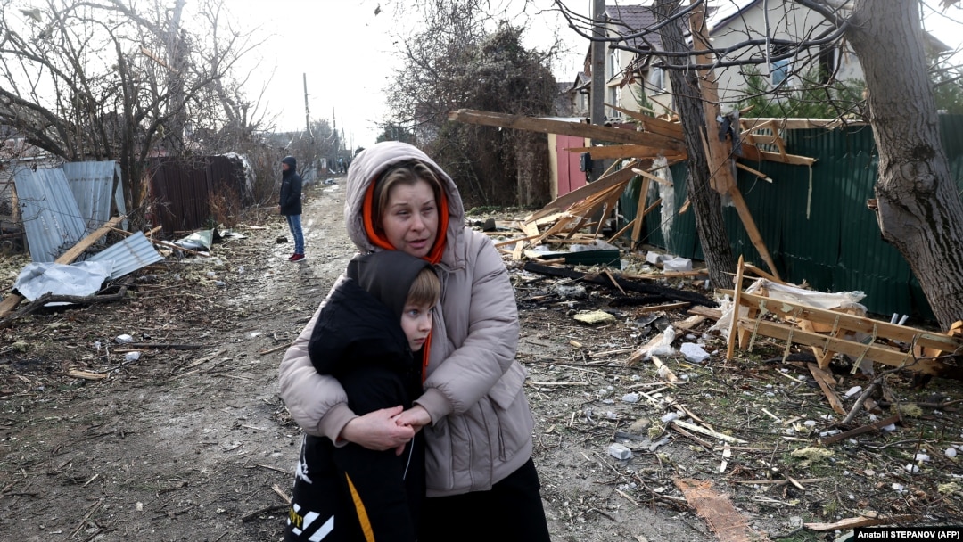 Residents stand among debris on the street outside a house destroyed as a result of a drone attack in Tayirove, Odesa region, on December 17.
