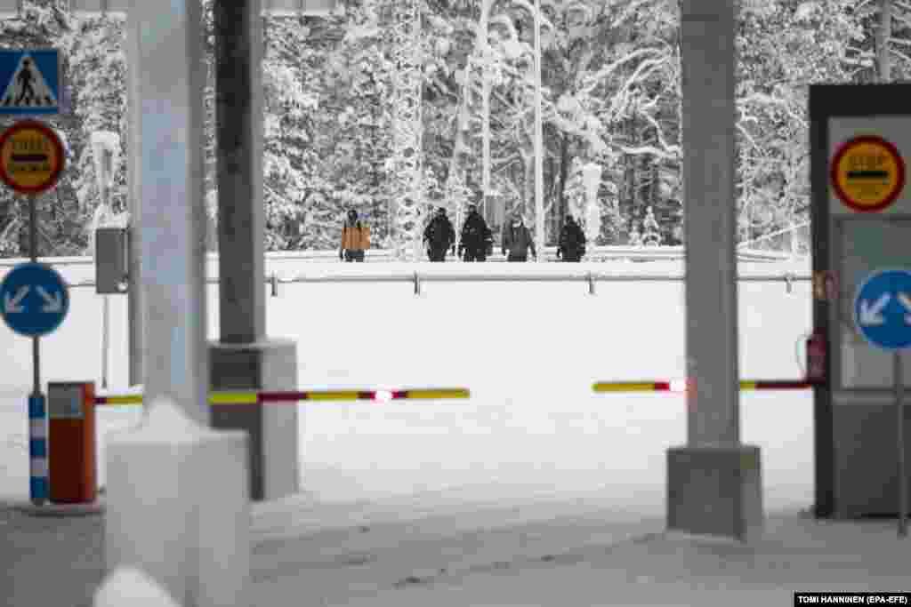 Migrants are accompanied by Finnish border guards as they arrive at the Raja-Jooseppi border station in Lapland on November 27.&nbsp; According to the Finnish Border Guard, about 900 asylum seekers from countries including Afghanistan, Kenya, Morocco, Pakistan, Somalia, Syria, and Yemen crossed into Finland from Russia in November, up from fewer than one per day the month before.