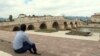 Aliraza Kuresi sits on the steps in front of the bridge