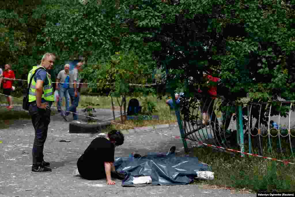 O femeie stă lângă trupurile rudelor ei ucise. &nbsp; &nbsp;