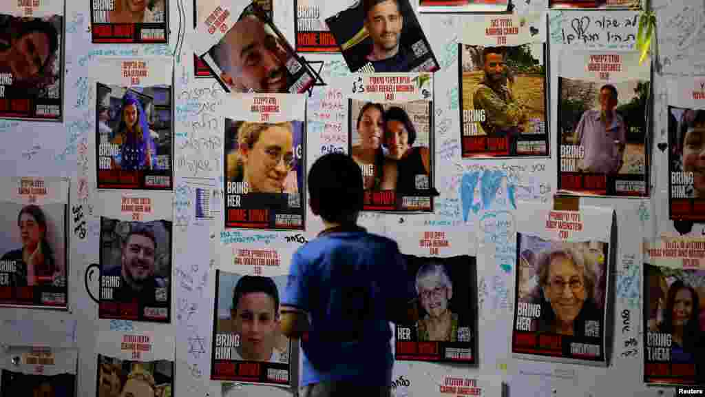 Egy kisfiú nézi az eltűnt izraelieket mutató plakátokat Tel-Avivban, miközben a híreket várják 2023. november 25-én azokról, akiket a Hamász várhatóan szabadon enged.&nbsp;A WAFA palesztin hírügynökség szerint az Izrael által szabadon engedett harminckilenc palesztin fogoly mind tizenéves