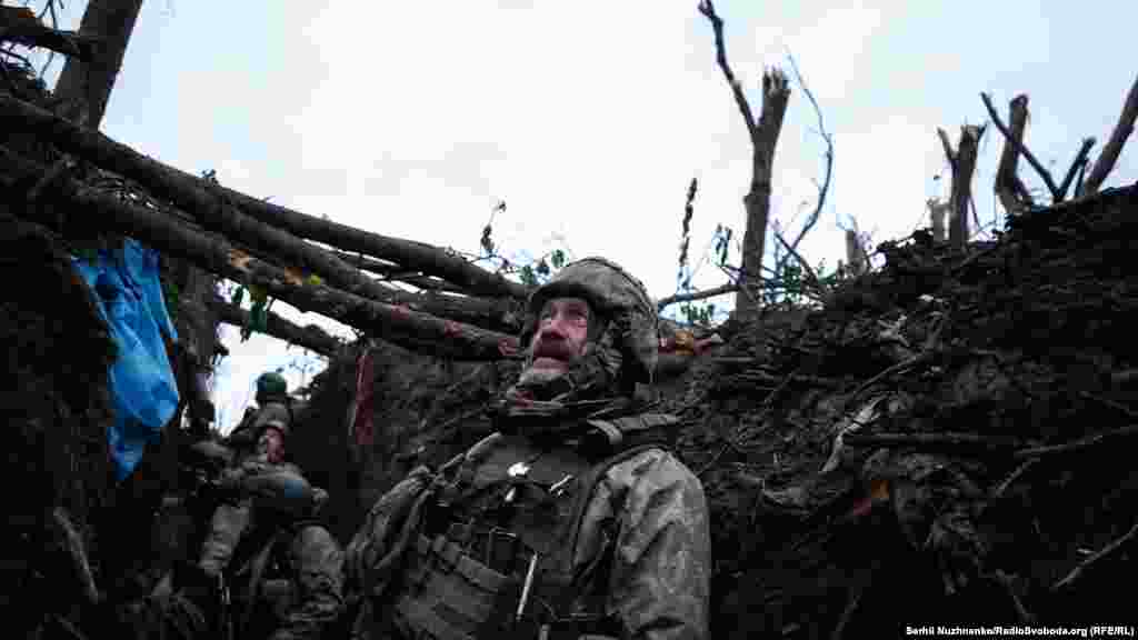 Украинский военный смотрит из своего окопа во время перестрелки с российскими войсками, 11 мая 2023 года. 15 мая украинские военные заявили о наступлении ВСУ в окрестностях Бахмута, города на востоке страны, сообщив о первой успешной контратаке&nbsp;