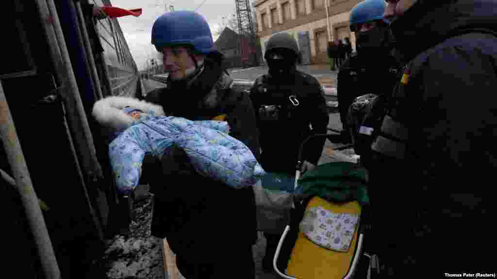 Az ukrán mentőszolgálat egyik dolgozója átad egy csecsemőt az édesanyjának egy evakuáló vonatnál Pokrovszkban, miután megszaporodtak az Avgyijivka környéki településekre mért orosz rakétacsapások. A kép 2024. február 20-án készült