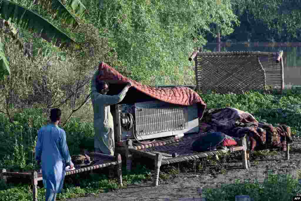 In the Charsadda district of Khyber Pakhtunkhwa Province, residents salvage their personal belongings by placing them on cots above mud left over from the floodwaters.