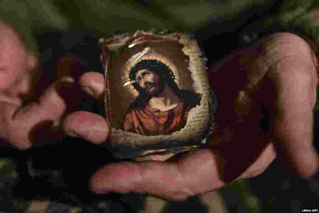 A partially burned prayer book is held by a Ukrainian soldier in a shelter.