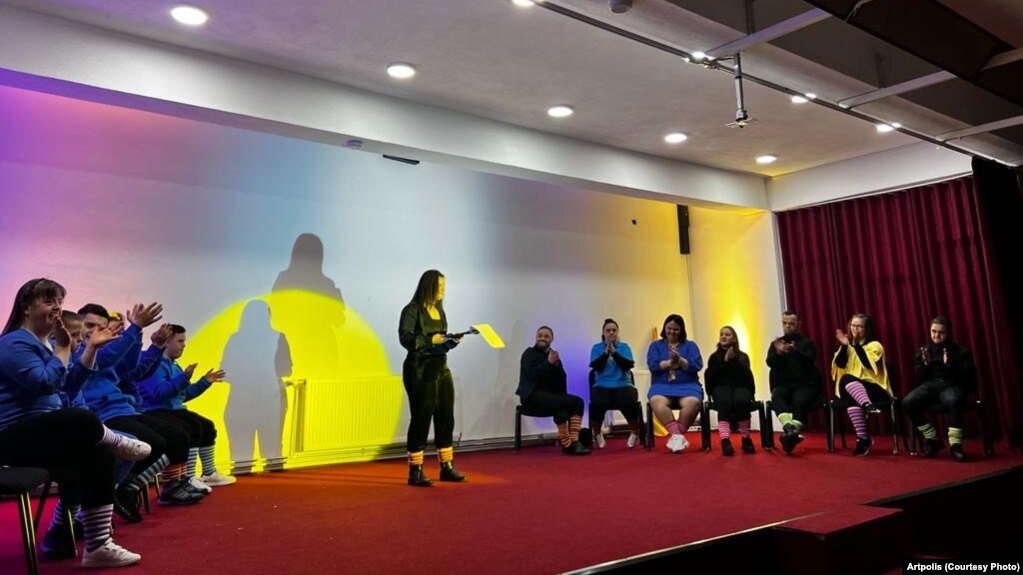 Ndalore Likaj duke moderuar shfaqjen "Trisomy Love", e rrethuar nga anëtarët e tjerë të shoqatës Down Syndrome Kosova në Prizren.