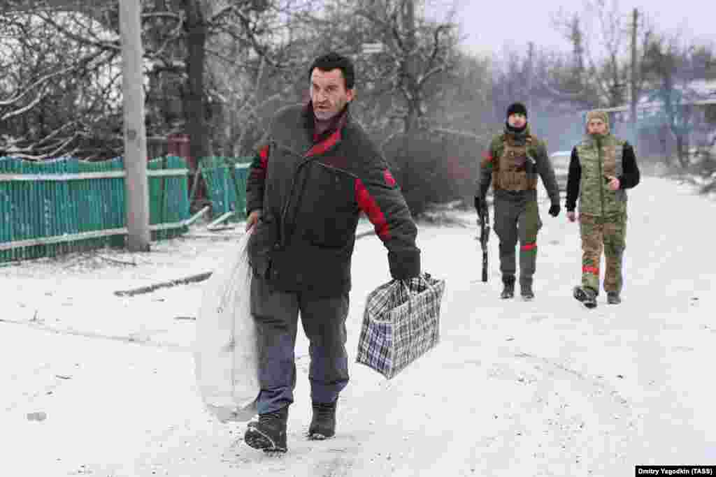 Мъж се разхожда из предградие на Авдиивка пред руски войници на 19 февруари. След като руските сили наближиха Авдиивка през февруари, десетки от останалите жители напуснаха града. Не е ясно колко са останали.