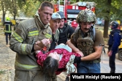 Paramedics carry a person rescued from an apartment building after a Russian air strike in Kharkiv on August 30.