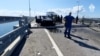 Anchetatori ruși și membri ai serviciilor de urgență adună probe lângă o mașină distrusă pe secțiunea avariată a podului, la 17 iulie.