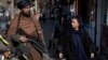 A Taliban fighter and an Afghan woman eye one another in Kabul in December 2022.<br />
<br />
Since their return to power in August 2021, the hard-line Islamists have waged a brutal crackdown on dissent and reintroduced their extreme and tribal interpretation of Islamic Shari&rsquo;a law.