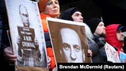 Demonstrators hold up pictures of Vladimir Putin and Aleksei Navalny at a rally near the Russian Consulate in New York following the announcement of Navalny's death on February 16.