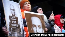 Protestuesit duke mbatur forografi të Vladimir Putinit dhe Aleksei Navalnyt gjatë një tubimi para Konsullatës Ruse në Nju Jork, pas njoftimit për vdekjen e kritikut të Kremlinit më 16 shkurt. 
