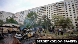 Украинские спасатели работают на месте обстрела российскими войсками жилого района в Харькове, 14 мая 2024 года
