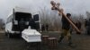 A man carries wooden crosses during a funeral ceremony of three children killed in what Moscow-installed officials say was a Ukrainian attack in Donetsk on March 17.