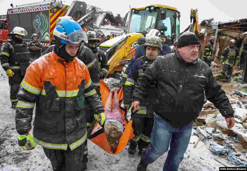 Рятувальники несуть тіло жінки, яка загинула під час російського ракетного удару по місту Зміїв, що на сході Харківщини, 8 січня 2024 року. Російські війська завдали масованої хвилі ракетних ударів по українських регіонах, забравши життя щонайменше чотирьох мирних жителів, поранивши щонайменше 40 і завдавши шкоди інфраструктурі та економічним об&rsquo;єктам, заявили офіційні представники влади