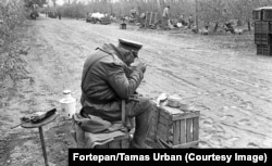 A prison warden rests a Kalashnikov on his lap while guarding inmates on labor duty in 1986.