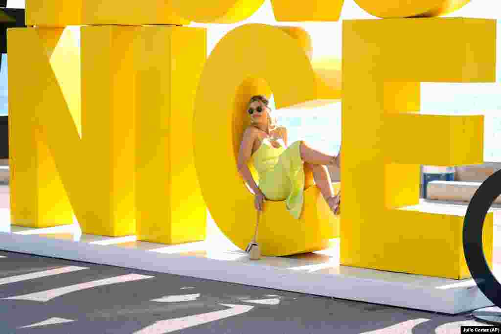 A tourist from Romania poses for a photograph on a sign along the oceanfront in Nice, France, ahead of the 2024 Summer Olympics. Nice will host six soccer matches during the Summer Olympics.