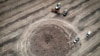 Un fermier adună recolta în jurul unui crater lăsat de o rachetă rusească în regiunea Dnipropetrovsk, Ucraina, în iulie 2022.