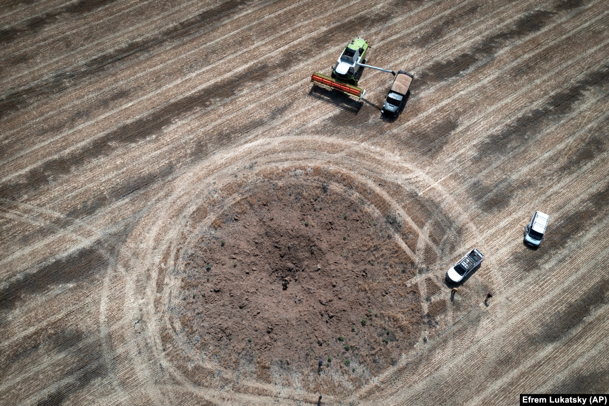 Farmers harvest around a crater left by a Russian rocket. With the blockade of their ports, in addition to the dangers of unexploded ordnance littering their fields and a decrease in manpower as the able-bodied head to the front, many of Ukraine&rsquo;s farmers are struggling to provide their produce to those in developing nations who are battling with hunger.