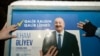 AZERBAIJAN - Electoral officials stick up a poster of Azerbaijani President Ilham Aliyev in Baku on January 15, 2024, on the first day of the official campaigning for the February 7 presidential election.