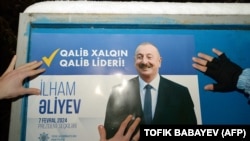AZERBAIJAN - Electoral officials stick up a poster of Azerbaijani President Ilham Aliyev in Baku on January 15, 2024, on the first day of the official campaigning for the February 7 presidential election.