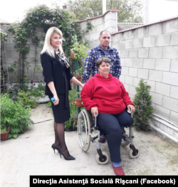 Tatiana Bezerdic (în scaun rulant) alături de soțul său, care i-a fost asistent personal timp de opt ani, împreună cu reprezentanta Direcției asistență socială a sectorului Rîșcani din Chișinău.