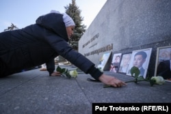Женщина кладёт цветы у портретов погибших во время Январских событий. Алматы, 5 января 2024 года