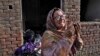 Egy keresztény nő sír felgyújtott otthona előtt Dzsaranvala városában, Pakisztánban 2023. augusztus 17-én
