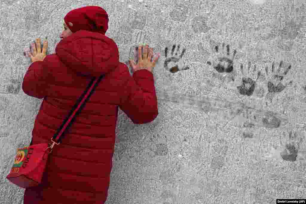 Žena ostavlja otiske ruku na zidu prekrivenom mrazom u Sankt Peterburgu, Rusija.