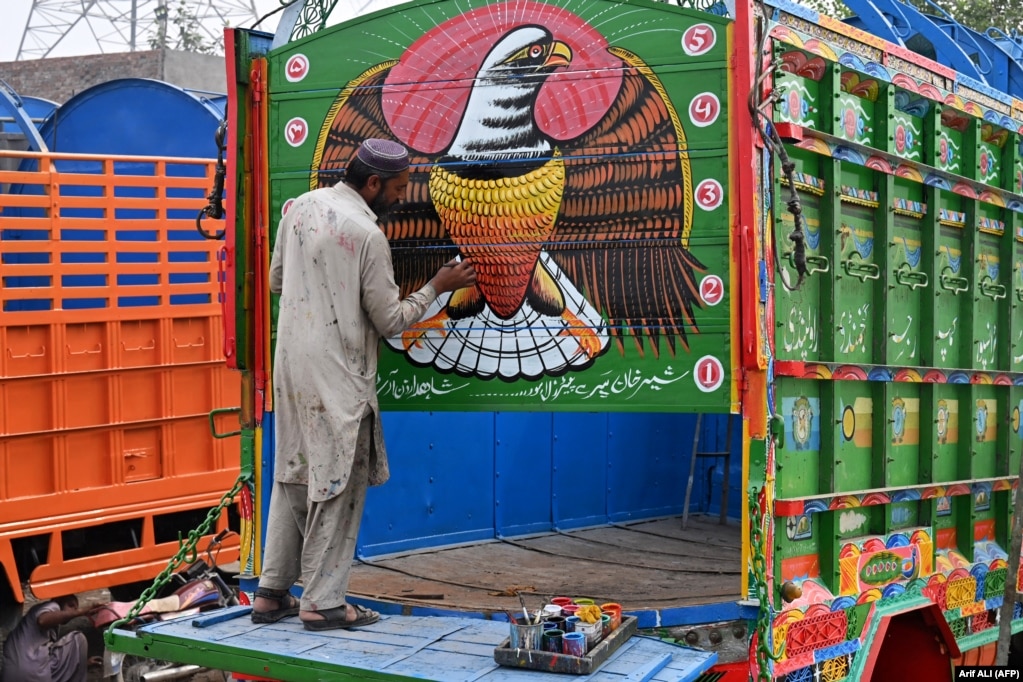 Një burrë duek ngjyrosur një kamion në punëtorinë e tij në Lahore, Pakistan.