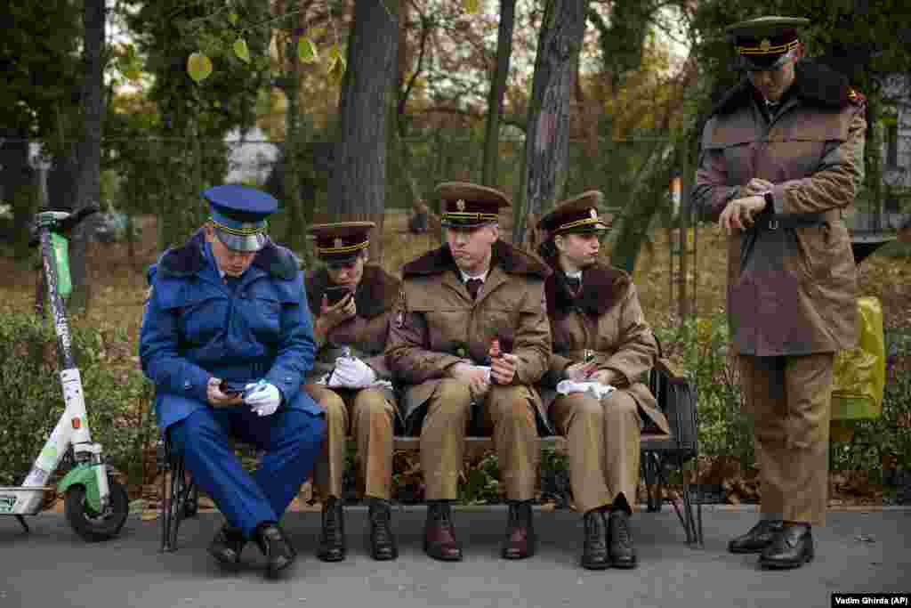 Military cadets sit on a bench before taking part in the National Day parade in Bucharest on December 1.