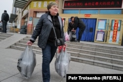 Женщина выходит из торгового центра с покупками. Китай, Международный центр приграничного сотрудничества «Хоргос». 20 марта 2024 года