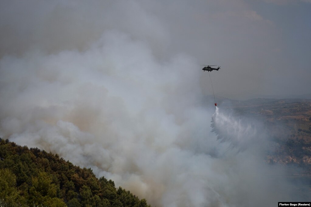 Helikopteri zjarrfikës duke bombarduar me ujë flakët në një pyll afër Cakranit.