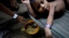 Egy őslakos janomami gyermeket rizs és farofa (brazil puliszkaféle) keverékével etet az édesanyja egy egészségügyi központban, a janomami őslakosok földjén, Roraima államban, Brazíliában 2024. január 10-én. A brazil egészségügyi minisztérium adatai szerint tavaly háromszáznyolc&nbsp;janomami halt meg betegség, alultápláltság és erőszak következtében. A halálesetek ötven százaléka négy év alatti gyermeket érintett. A bányászok által behurcolt malária okozta halálozások száma 2023-ban megkétszereződött 2022-höz képest