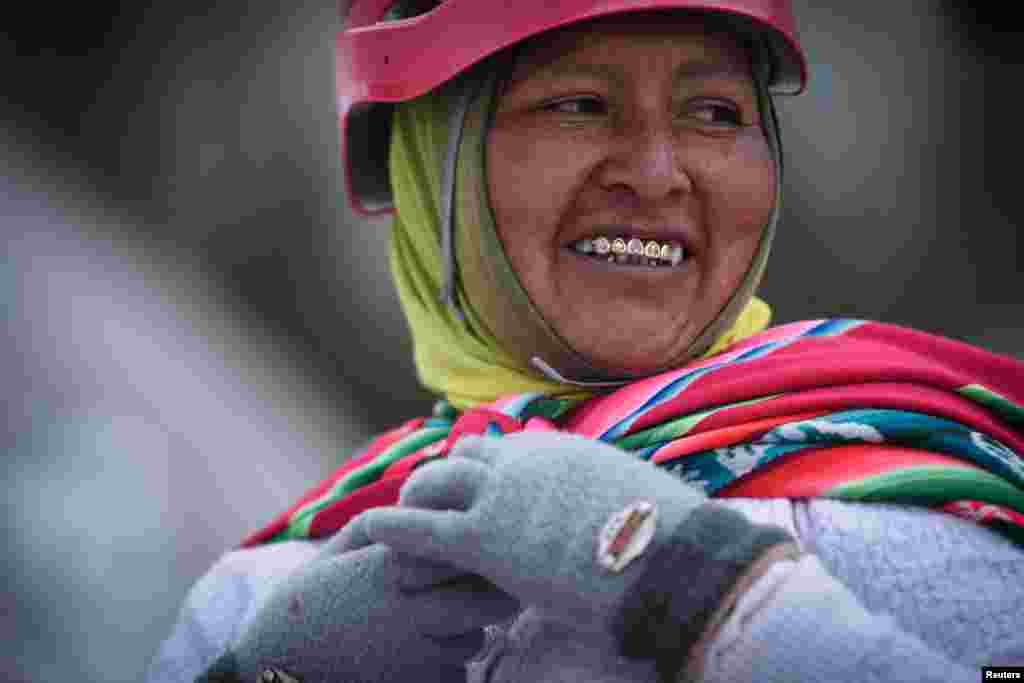 Alicia Quispe Tincuta, 40 vjeç, një anëtare e alpinistëve me funde te kuqe - cholita, shikon mbi supe ndërsa ngjitet në malin e mbuluar me borë Huayna Potosi, afër El Altos në Bolivi.
