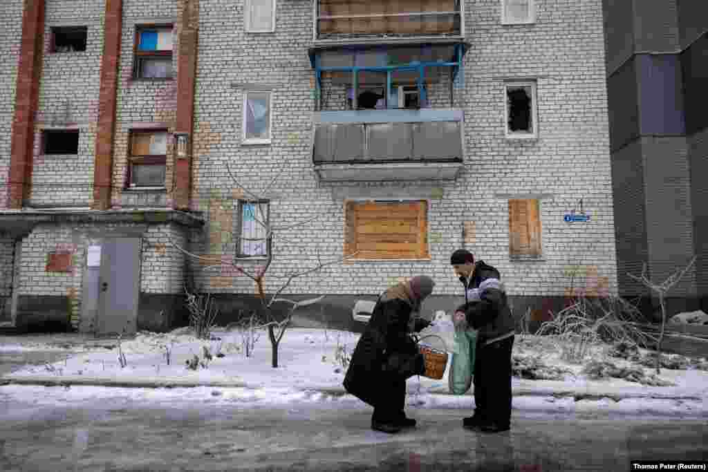 A volunteer delivers groceries to an elderly woman on one of Lyman&#39;s ice-covered streets. Most of the city&#39;s 20,000 residents fled after Russia launched the full-scale invasion of Ukraine in 2022. Only about one-quarter of the population remains. &nbsp;