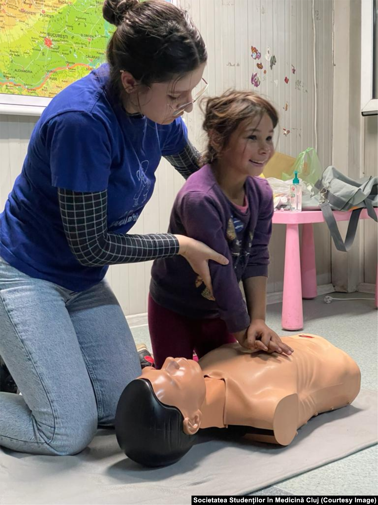 O studentă voluntar de la „Micii sanitari” (de la Societatea Studenților în Medicină Cluj) îi explică unui copil din Pata Rât, Cluj, cum să acorde primul ajutor în caz de urgență.