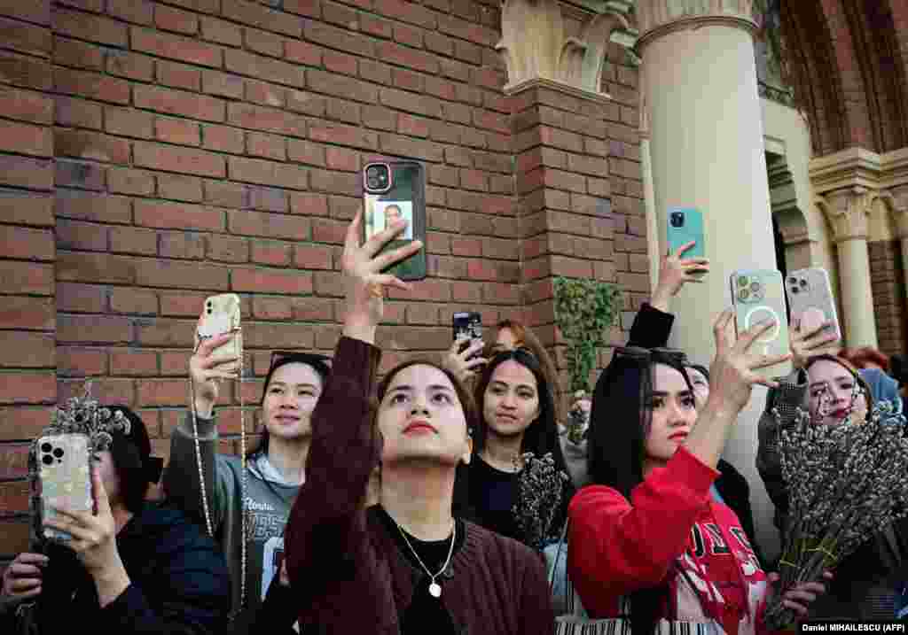 Spectators use their mobile phones to film a procession to celebrate the catholic Palm Sunday holiday in Bucharest, one week ahead of Easter holiday, on March 24.
