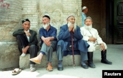 Китайские мусульмане-уйгуры сидят возле мечети в городе Кука, в северо-западном регионе Китая Синьцзян, май 2022 года