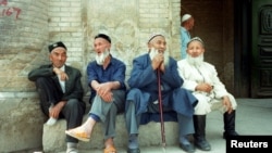 Китайские мусульмане-уйгуры сидят возле мечети в городе Кука, в северо-западном регионе Китая Синьцзян, май 2022 года.