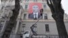 A man installs an anti-Putin poster on a building in the Latvian capital, Riga. (file photo)