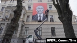 A man installs an anti-Putin poster on a building in the Latvian capital, Riga. (file photo)